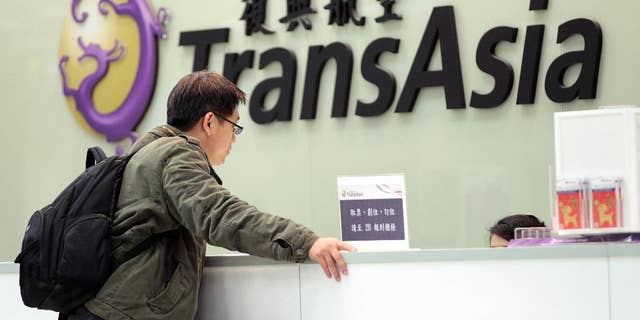 FILE- In this Saturday, Feb. 7, 2015, file photo, a passenger waits at the ticket counter of TransAsia Airways at the Songshan Airport in Taipei, Taiwan. Taiwanese airline TransAsia has announced it is shutting down following financial losses and two fatal crashes. TransAsia chairman Vincent Lin said Tuesday the airline, which served cities in China, Japan and Southeast Asia, was unable to reverse widening losses or raise additional money. (AP Photo/Wally Santana, File)