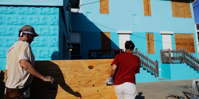Paulita Kundid, right, and her brother Mike Kundid board up their apartment building ahead of Hurricane Irma in Daytona Beach, Fla., Friday, Sept. 8, 2017. Coastal residents around South Florida have been ordered to evacuate as the killer storm closes in on the peninsula for what could be a catastrophic blow this weekend. (AP Photo/David Goldman)