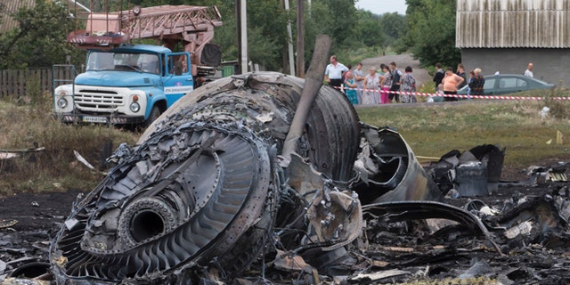 Local citizens, background, look at the site of a crashed Malaysia Airlines passenger plane near the village of Rozsypne, Ukraine, eastern Ukraine Friday, July 18, 2014. Rescue workers, policemen and even off-duty coal miners were combing a sprawling area in eastern Ukraine near the Russian border where the Malaysian plane ended up in burning pieces Thursday, killing all 298 aboard. (AP Photo/Dmitry Lovetsky)