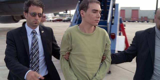 FILE - In this June 18, 2012 file photo provided by Montreal Police, Luka Rocco Magnotta is taken by police from a Canadian military plane to a waiting van in Mirabel, Quebec. Magnotta dropped his appeal Wednesday, Feb. 18, 2015 of a life sentence for killing and dismembering his Chinese lover and mailing his body parts to schools and political parties. Magnotta, 32, was sentenced to life in prison last December in the slaying and dismemberment of Jun Lin, a 33-year-old Chinese engineering student who had been living in Canada since 2011. (AP Photo/Montreal Police)