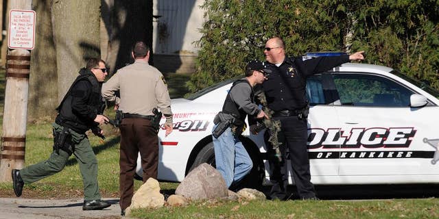 Police officers from the City of Kankakee and Kankakee County search for prison escapee Kamron T. Taylor in Kankakee, Ill., Wednesday, April 1, 2015. Authorities say Taylor, a convicted murderer who escaped from jail earlier in the day after beating a guard into unconsciousness, taking his keys and uniform and speeding off in his SUV. (AP Photo/The Daily Journal, Mike Voss)