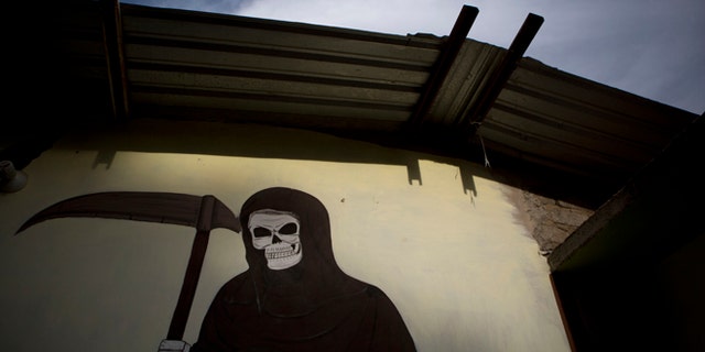 A mural of La Santa Muerte, or Saint Death, decorates the wall of a community center in Colonias, Michoacan state, Mexico, where vigilantes met with the families of a Tuesday shooting that took place in nearby Apatzingan, on Thursday, Jan. 8, 2015. Confrontations in Apatzingan began Tuesday when federal forces moved in to take control of city hall, which had been held for days by civilians whose demands and identities were unclear, according to Michoacan state Commissioner Alfredo Castillo. The second clash came when gunmen attacked soldiers who were transporting the seized vehicles to an impound lot, Castillo said. However, family members and witnesses tell a different story, one with a higher death toll. (AP Photo/Rebecca Blackwell)