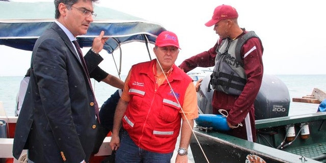 In this photo provided by Venezuela's Ministry of the Interior and Justice Press Office, Italy's ambassador to Venezuela Paolo Serpi, left, speaks with rescue team members prior to their continued search for a missing plane off Los Roques, Venezuela, Monday, Jan. 7, 2013. The search for a missing plane carrying Italian fashion executive Vittorio Missoni and five other people has entered its fourth straight day on Monday with no signs of the aircraft. The small, twin-engine plane was reported missing hours after taking off Friday from Los Roques, a string of islands and islets popular among tourists for their white beaches and coral reefs. (AP Photo/Venezuela Ministry Interior and Justice Office Press)