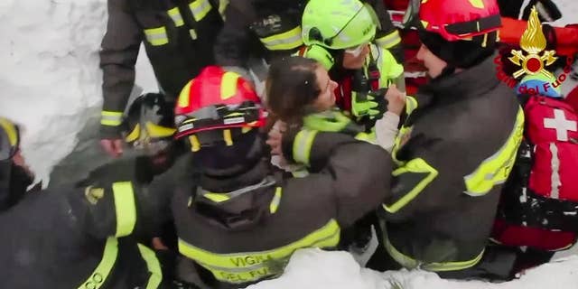 This frame from video shows Italian firefighters pulling out a woman from under the snow and debris.