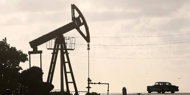 FILE - In this July 11, 2014 file photo, an oil well pump operates in Boca de Jaruco, Cuba. Officials are warning of tough times with authorities ordering energy-saving measures and some state entities reducing hours of operation. (AP Photo/Desmond Boylan, File)