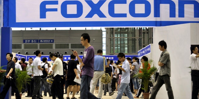 May 22, 2010: Visitors to a job fair walk past the Foxconn recruitment area in Shenzhen in south China's Guangdong province.
