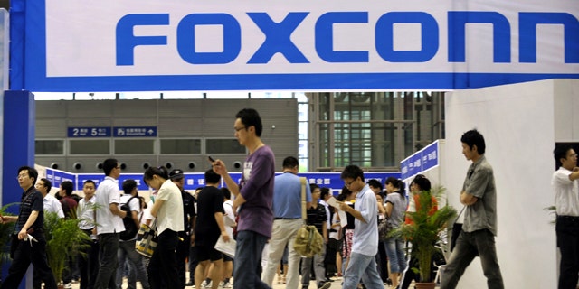 May 22, 2010: Visitors to a job fair walk past the Foxconn recruitment area in Shenzhen in south China's Guangdong province.