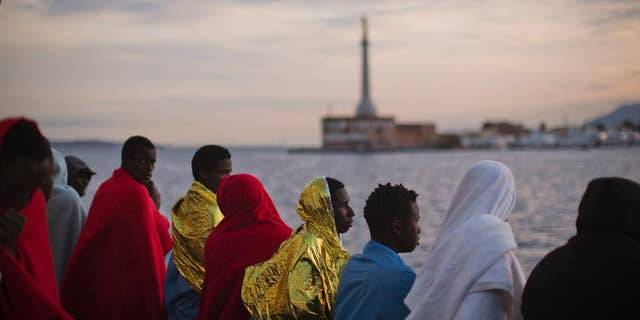 Wrapped in blankets, Sub-Saharan migrants look at the coast inside the Golfo Azzurro rescue vessel as they are arriving at the port of Messina, in Italy, with more than 299 migrants aboard the ship rescued by members of Proactive Open Arms NGO, on Sunday, Jan. 29, 2017. (AP Photo/Emilio Morenatti)
