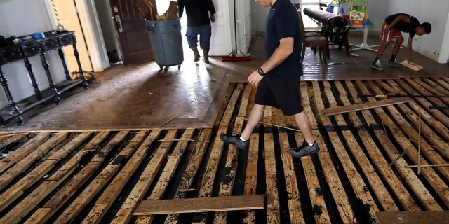 Michael Saghian walks across the living room of his home damaged by floodwaters from Tropical Storm Harvey on Wednesday, Aug. 30, 2017, in Houston. (