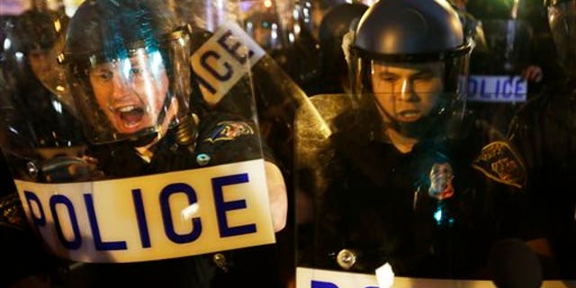 Police in riot gear push back on media and a crowd gathering in the street after a 10 p.m. curfew went into effect Thursday, April 30, 2015, in Baltimore. The curfew was imposed after unrest in the city over the death of Freddie Gray while in police custody. (AP Photo/David Goldman)
