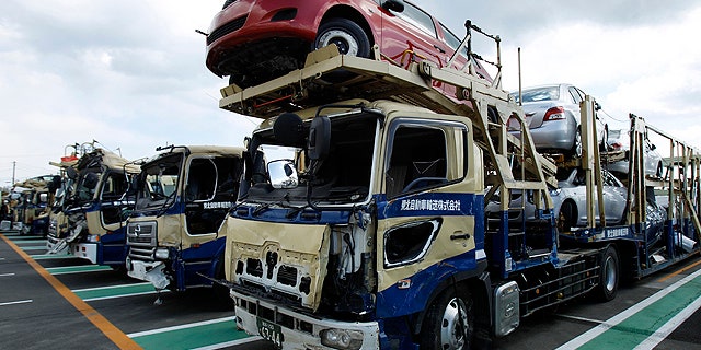 New vehicles and their delivery trucks damaged by the March 11 tsunami sit lined in a Toyota parking lot at Sendai port, Miyagi Prefecture, northeastern Japan, Monday, March 28, 2011. The earthquake and tsunami and subsequent damage to the Fukushima Dai-ichi nuclear power plant have disrupted the flow of the Japanese auto industry that might affect Japan-imported cars around the world. (AP Photo/Wally Santana)