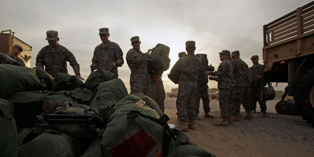U.S. Army soldiers from 1st Cavalry Division, based at Fort Hood, Texas, load their baggage as they begin their journey home after a deployment in Iraq, at Camp Virginia, Kuwait, Dec. 15, 2011. (AP Photo/Maya Alleruzzo)