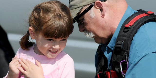This Friday, Sept. 19, 2015 photo shows Elizabeth "Lizzy" Myers, left, being fitted for a microphone by a CBS sound man before taping a segment in Lucas, Ohio. Myers, a 5-year-old Ohio girl whose parents created a "visual bucket list" for her because she's slowly going blind is going to meet Pope Francis. Steve Myers told the Mansfield News Journal on Thursday, March 24, 2016, that his daughter Elizabeth "Lizzy" Myers is visiting the Vatican next week. (Jason J. Molyet/News Journal via AP) NO SALES; MANDATORY CREDIT