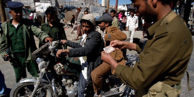 Yemeni soldiers check a motorbike driver at a checkpoint in Sanaa, Yemen, Saturday, Jan. 5, 2013. Yemeni police have said that more than 40 security and army personnel were shot dead in drive-by attacks involving motorbikes throughout Yemen in 2012. (AP Photo/Hani Mohammed)