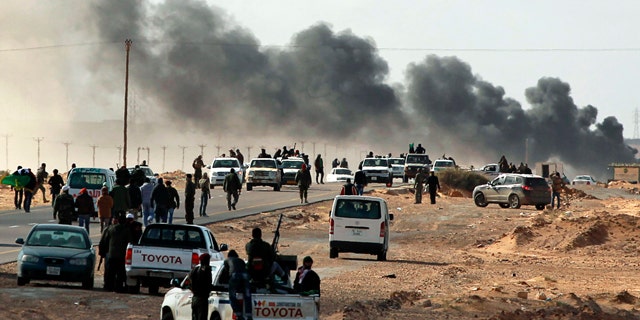 Smoke rises from heavy shelling as Libyan rebels who are part of the forces against Libyan leader Moammar Gadhafi retreat during a battle with Gadhafi's troops, outside the town of Bin Jawwad, eastern Libya, Sunday, March 6, 2011