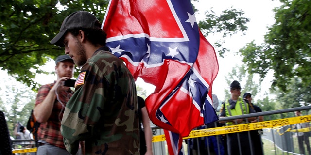 A white nationalist carries the Confederate flag as he arrives for a rally in Charlottesville, Virginia on Aug. 12, 2017.