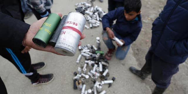Migrant men shows used tear gas canisters apparently used by Macedonian police during yesterday riots at the fence of a makeshift camp in the northern Greek border point of Idomeni, Greece, Monday, April 11, 2016. More than 12,000 people have been stuck at the Idomeni border point for more than a month hoping that it would reopen. (AP Photo/Amel Emric)