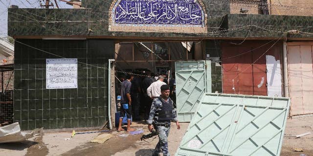 Security forces and civilians inspect the damage outside Imam Ali mosque in New Baghdad, Iraq, Monday, Aug. 25, 2014. Iraqi officials say a wave of attacks targeting commercial areas in and outside Baghdad has killed and wounding scores of people. They say the deadliest of Monday's bombings was carried out by a suicide bomber who blew up himself among Shiite worshippers who were leaving Imam Ali mosque after noon prayers in the capital's eastern New Baghdad area, killing at least 15 people and wounding 32 others.(AP Photo/ Khalid Mohammed)