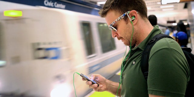 FILE: Aug. 13, 2011: A man checks his cell phone while waiting for a BART train at San Francisco's Civic Center station, in Calif.