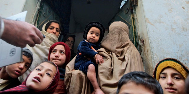 In this Dec. 28, 2010 file photo, a Pakistani health worker, left, visits families to inform them on polio in Peshawar, Pakistan. In his 2009 speech to the Muslim world, President Obama announced a new effort to eradicate polio, which persists in three Muslim countries.