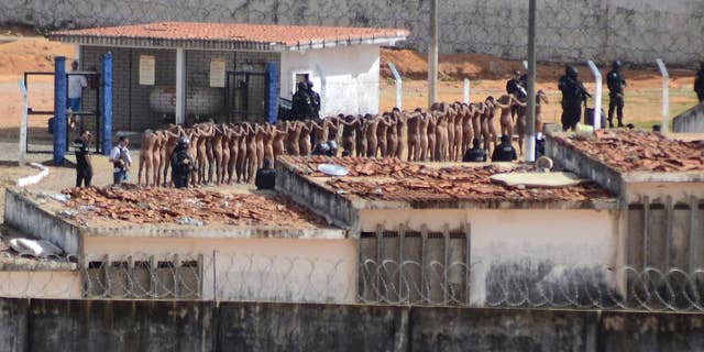 Naked inmates stand in line while surrounded by police after a riot at the Alcacuz prison in Nisia Floresta, Rio Grande do Norte state, Brazil, Sunday, Jan. 15, 2017. Security authorities said Sunday they have regained control of two Brazilian prisons after several inmates were killed during a riot, the latest in a string of prison disturbances across the country. (Frankie Marcone/Futura Press via AP) NAO PUBLICAR NO BRASIL