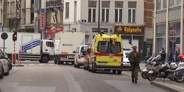 In this framegrab taken from APTN, a soldier walks along a street in Brussels, Belgium, Wednesday July 20, 2016. Police in Brussels say they arrested a man acting suspiciously and wearing heavy clothes with wires hanging out, in the area of place Monnaie. Police closed the area and evacuated people surrounding the area. (AP Photo/APTN)