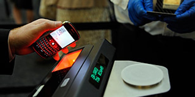 A Continental Airlines representative demonstrates how passengers can get boarding passes electronically on their cell phones or PDA's which are then scanned by security officers at the checkpoint, the need for paper boarding pass is eliminated. TSA and Continental Airlines expanded their paper less boarding program at the San Francisco International Airport today, Tuesday, Sept., 1, 2009.(AP Photo/Russel A. Daniels)