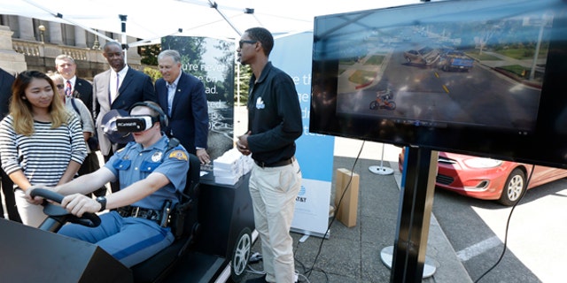 Washington State Patrol cadet Cody Fath wears goggles as he views a virtual reality depiction of several distracted driving scenarios during a press event, Monday, July 17, 2017, at the Capitol in Olympia, Wash.