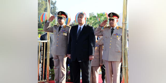 In this photo released by the Egyptian Presidency, Egypt's interim President Adly Mansour, center, Defense Minister Abdel-Fatah el-Sissi, left, and other officials visit the Tomb of the Unknown Soldier and President Anwar Sadat's memorial as part of celebrations marking the 40th anniversary of the start of the 1973 Middle East war in which Egyptian forces made initial gains against Israel, Saturday, Oct. 5, 2013.   Egypt's army is on high alert ahead of expected mass demonstrations by supporters of ousted Islamist President Mohammed Morsi timed to coincide with annual celebrations honoring the military, a combination many fear will lead to a new round of violence. (AP Photo/Egyptian Presidency)