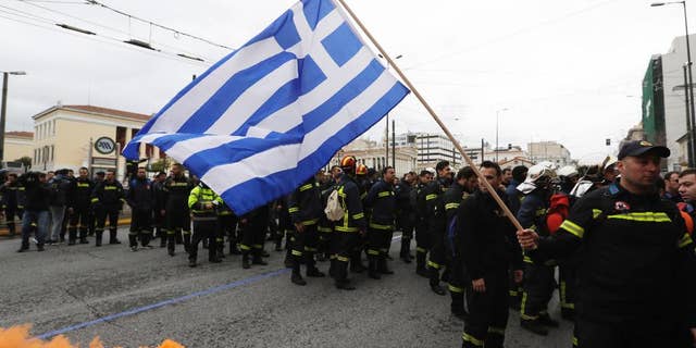 A firefighter holds a Greek flag during a protest in central Athens, on Wednesday, Feb. 8, 2017. Hundreds of firefighters in uniform have taken to the streets of the Greek capital to protest hiring conditions. (AP Photo/Thanassis Stavrakis)