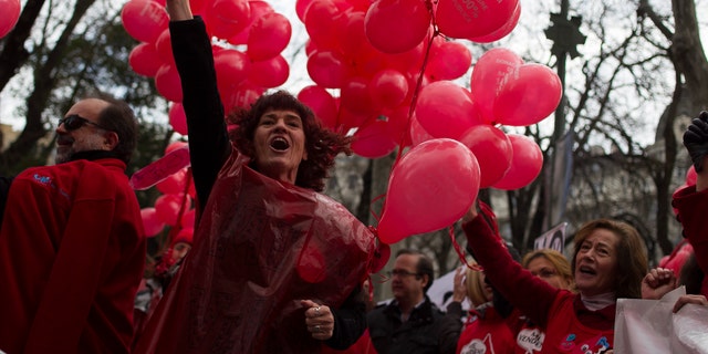A protestor shouts slogans as she carries red balloons during a demonstration against the Madrid's regional government plans to privatize the blood donation centers, in Madrid, Spain, Sunday, Feb. 16, 2014. (AP Photo/Gabriel Pecot)