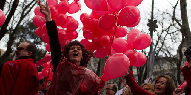 A protestor shouts slogans as she carries red balloons during a demonstration against the Madrid's regional government plans to privatize the blood donation centers, in Madrid, Spain, Sunday, Feb. 16, 2014. (AP Photo/Gabriel Pecot)