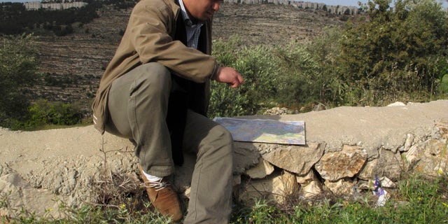 In this Friday, April 19, 2013 photo, George Abu Eid, 22, sits with the map of the area near the village of Beit Jala in the Cremisan Valley, West Bank. Abu Eid's family land is threatened with expropriation to build Israel’s separation barrier. Palestinian residents of this Christian village are hoping the new pope can succeed where others have failed as they press the Israeli government to drop plans to build a stretch of its West Bank separation barrier through their ancestral lands. (AP Photo/Diaa Hadid)
