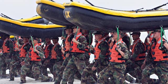 FILE - In this May 14, 2009 file photo, Navy SEAL trainees carry inflatable boats at the Naval Amphibious Base Coronado in Coronado, Calif. In a highly unusual move, the training death of an aspiring Navy SEAL, 21-year-old Seaman James Derek Lovelace, has been ruled a homicide by the San Diego County Medical Examiner. Lovelace was in his first week of training in Coronado, Calif., when he died. (AP Photo/Denis Poroy, File)