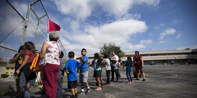 A teacher holds a flag as she evacuates with her students during the "Great ShakeOut" earthquake drill at Marlton School in Los Angeles, California October 15, 2015. (REUTERS/Mario Anzuoni)