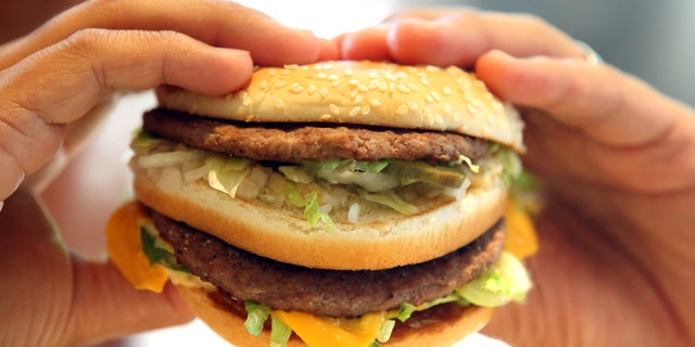 man's hands, holding onto a burger