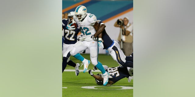 Miami Dolphins tight end Charles Clay (42) breaks up tackles by San Diego Chargers strong safety Marcus Gilchrist (38) and linebacker Donald Butler (56) for a 39-yard run for a touchdown during the second half of an NFL football game, Sunday, Nov. 17, 2013, in Miami Gardens, Fla. (AP Photo/Wilfredo Lee)