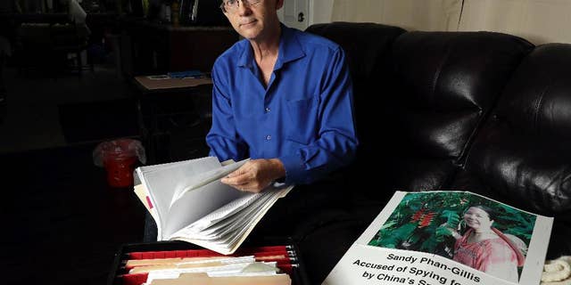 FILE - In this Oct. 4, 2016, file photo, Jeff Gillis looks through documents he has collected in support of his wife in Houston. The husband of U.S. citizen Phan "Sandy" Phan-Gillis, who has been charged in China with spying, has spent months trying to prove his wife's innocence with the little information he had. A Chinese court on Tuesday, April 25, 2017, sentenced Phan-Gillis to 3 ½ years in prison for spying charges, in a case that has drawn criticism from the United Nations and human rights advocates. (AP Photo/David J. Phillip, File)