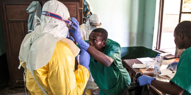 In this photo taken Saturday, May 12, 2018, health workers don protective clothing as they prepare to attend to patients in the isolation ward to diagnose and treat suspected Ebola patients, at Bikoro Hospital in Bikoro, the rural area where the Ebola outbreak was announced last week, in Congo.