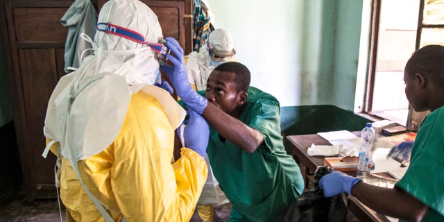 In this photo taken Monday, May 14, 2018, members of a Red Cross team don protective clothing before heading out to look for suspected victims of Ebola, in Mbandaka, Congo.