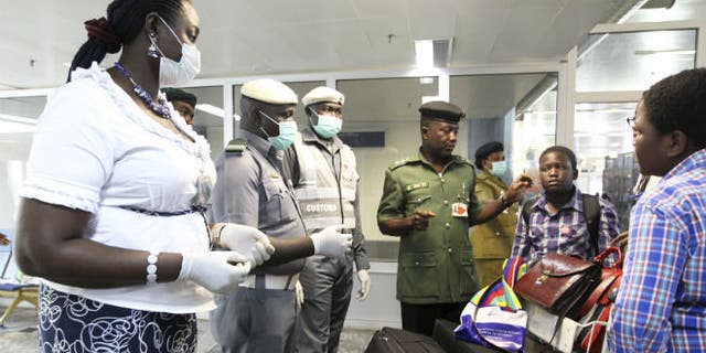 Nigerian custom officers wearing face masks and gloves screen passengers arriving at Nnamdi Azikiwe International Airport in Abuja August 11, 2014. CREDIT: REUTERS/AFOLABI SOTUNDE