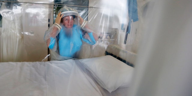 Senior Matron Breda Athan demonstrates putting on the protective suit which would be used if it becomes necessary to treat patients suffering from Ebola, at The Royal Free Hospital in London August 12, 2014. REUTERS/Suzanne Plunkett/Files