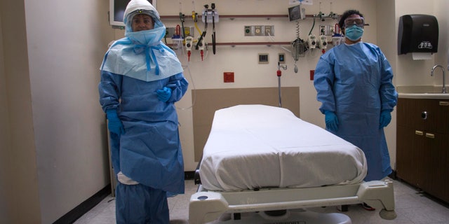 Health care workers display protective gear, which hospital staff would wear to protect them from an Ebola virus infection, inside an isolation room as part of a media tour of the emergency department of Bellevue Hospital in Manhattan, New York October 8, 2014. REUTERS/Adrees Latif
