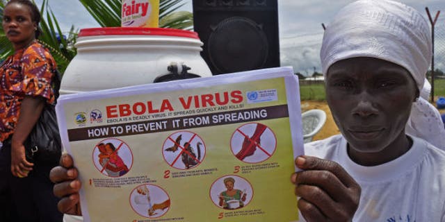 A Liberian woman holds up a pamphlet with guidance on how to prevent the Ebola virus from spreading, in the city of Monrovia, Liberia, Thursday, Aug. 14, 2014. (AP Photo/Abbas Dulleh)