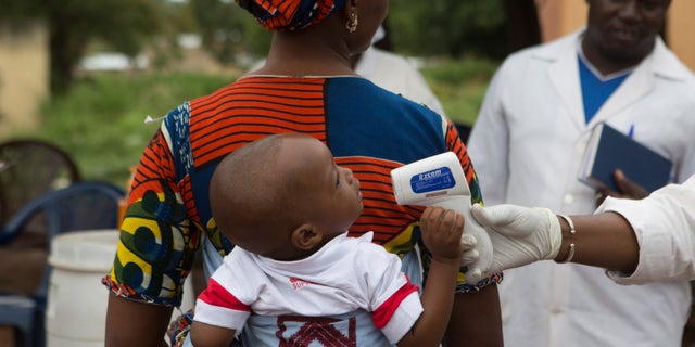 A health worker checks the temperature of a baby entering Mali from Guinea at the border in Kouremale, October 2, 2014. REUTERS/Joe Penney