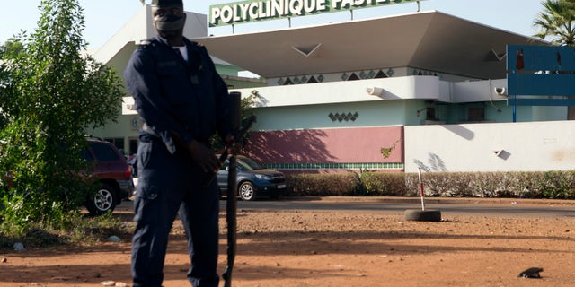 A police officer stands guard outside the quarantined Pasteur Clinic in Bamako November 12, 2014. REUTERS/Joe Penney