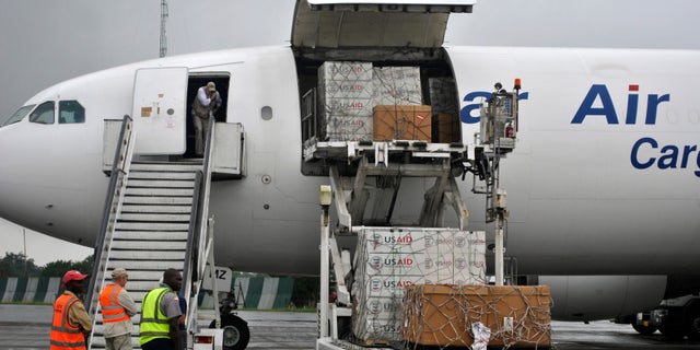 Workers are seen as the first consignment of U.S. Agency for International Development (USAID) medical equipment towards the fight against Ebola is offloaded at the Roberts International Airport in Monrovia, August 24, 2014. REUTERS/James Giahyue
