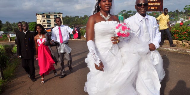 In this photo taken on Saturday, Nov. 15, 2014, an unidentified couple that just got married walk in a park used for wedding photography in the city of Monrovia, Liberia. (AP Photo/ Abbas Dulleh)