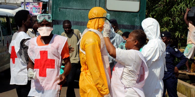 A health worker fixes another health worker's protective suit in the Aberdeen district of Freetown, Sierra Leone, October 14, 2014. REUTERS/Josephus Olu-Mammah