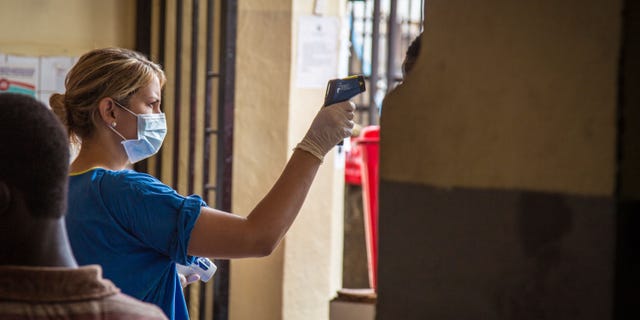 In this photo taken on Friday, Aug. 29, 2014, a health worker measures a patient's temperature at the Connaught Hospital, which has suffered the loss of medical workers in the past from the Ebola virus, in Freetown, Sierra Leone. (AP Photo/ Michael Duff)